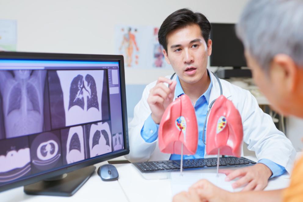 medical consultation - closeup back view asian elderly patient discussing lung health and ct scan x-ray results with doctor using organ model in the clinic